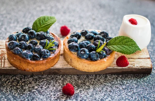 Eski dote ve gri arka planda ahududu ile taze krem vanilya krema ile Lezzetli yaban mersini tartalet. Ön görünüm. 