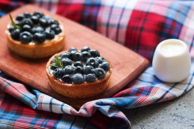 Damalı peçeteile tahta tahtada yaban mersini olan tartletler. Üstte görüntü