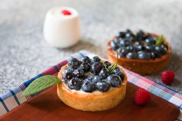 Bir damalı peçete ile ahşap tahta üzerinde yaban mersini ile Tartlets, ahududu taze çilek ile. Üstte görüntü