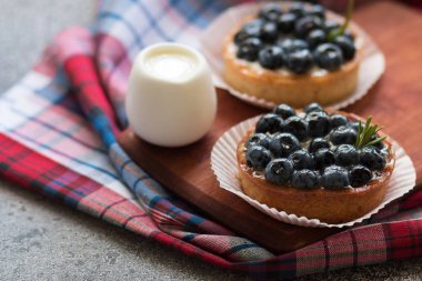 Bir damalı peçete ile ahşap tahta üzerinde yaban mersini ile Tartlets, ahududu taze çilek ile. Üstte görüntü
