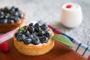 Bir damalı peçete ile ahşap tahta üzerinde yaban mersini ile Tartlets, ahududu taze çilek ile. Üstte görüntü