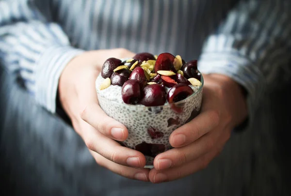Kiraz çilek, doğal yoğurt, chia, bir kızın elinde kabak çekirdeği ile Chia puding. Ön görünüm. 