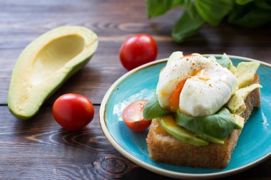 Yumurtalı ızgara beyaz ekmek mavi tabakta taze fesleğen yaprağı ve küçük domatesler. Üst görünüm. 