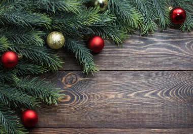 Köknar dalları, kırmızı ve altın Noel ağacı topları ahşap kahverengi arka planda. 