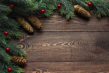 Çerçeve köknar ağacı dalları ve köknar kozalakları, kırmızı böğürtlenler, ahşap kahverengi bir yüzey üzerinde. 