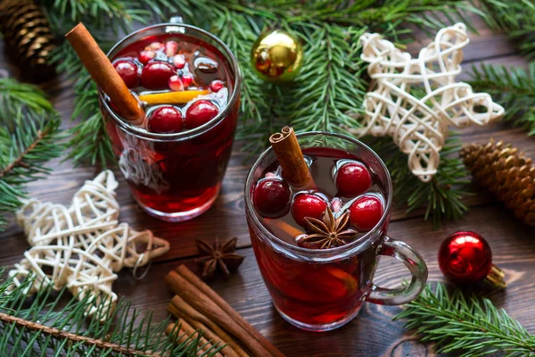 Mulled wine in glass mugs with berries, cinnamon sticks, star anise and Christmas Toys on brown wood table. — Stock Photo, Image