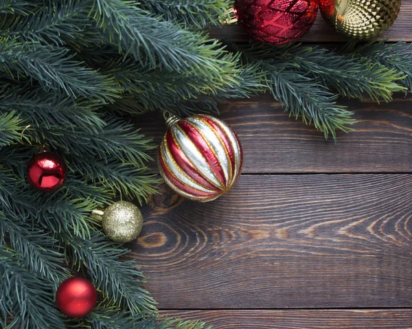 Köknar dalları, kırmızı ve altın Noel ağacı topları ahşap kahverengi arka planda. 