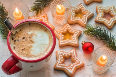 Beyaz masa üzerinde kahve fincanı ev yapımı Noel yıldızı şekerlemeli kurabiyeler içinde Noel ağaçları dalları ve Noel ağacı topları ve mumları olan kağıt bir paket.