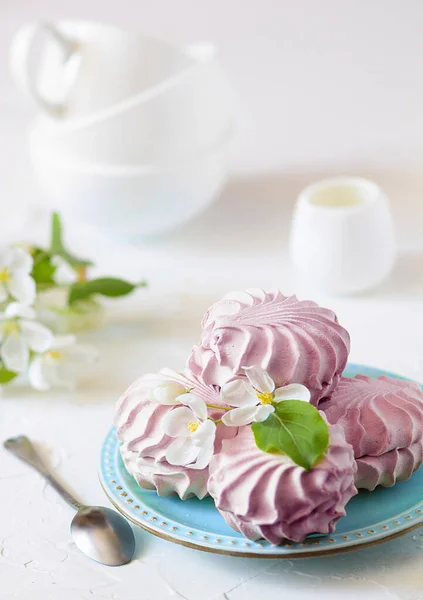 Domácí bobulové marshmallow na modrém talíři s květy jabloně a třemi šálky čaje na bílém stole. Selektivní soustředění. Pohled zepředu — Stock fotografie