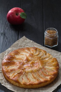Siyah bir masada kağıt üzerinde taze pişmiş elmalı turta..