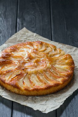 Siyah bir masada kağıt üzerinde taze pişmiş elmalı turta..