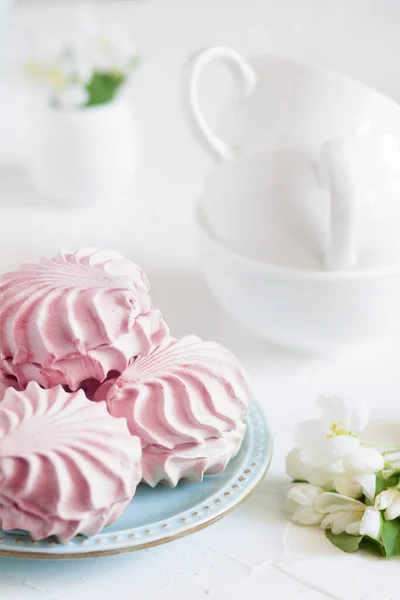 Marshmallow di bacche fatti in casa su un piatto blu con un albero di mele fiori e tre tazze da tè su un tavolo bianco. — Foto Stock