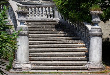 Yeşil bitki örtüsünün arka planında taş balyaları olan antik merdivenler.