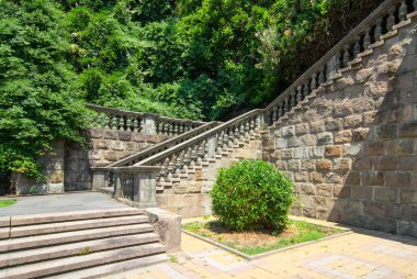 Yeşil bitki örtüsünün arka planında taş balyaları olan antik merdivenler.
