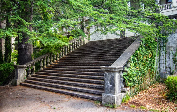 Ancient staircase with stone balusters on a background of green vegetation