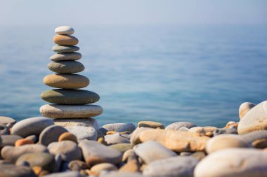 Güneşli bir günde sahile vuran deniz taşları piramidi.