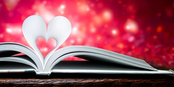 Book Heart Shape Pages On Wooden Table With Soft Glowing Romantic Red Background