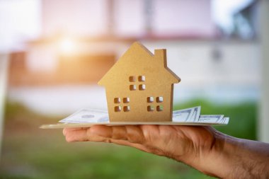 Bir iş adamının yatırım yapması ve para biriktirmesi veya finansal kurumlardan gelecek için ev satın alması, ev modeli kavramında dolar banknotlarıyla birlikte değerli bir değerdir..