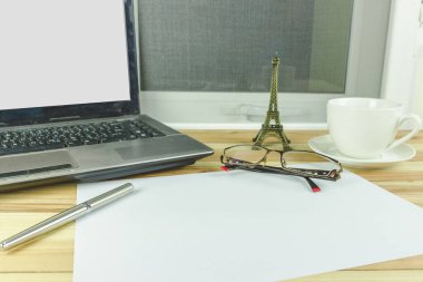 Masada gözlüklü, dizüstü bilgisayarı ve kalemi olan bir masa..