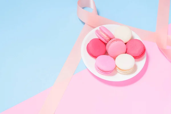 Kleurrijke bitterkoekjes of macaron op wit bord met roze lint op — Stockfoto