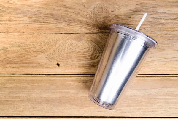 Top view  plastic tumbler cup with straw or tube on wooden backg