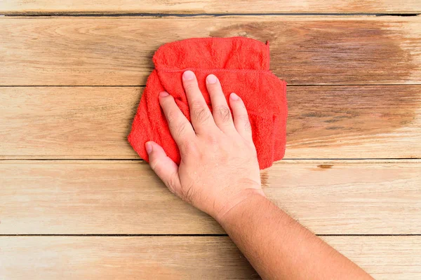 Die Hand eines Mannes wischt mit roten Lumpen den Holzboden. — Stockfoto