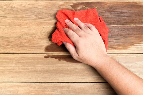 Iemands hand gebruiken rode lompen veeg de houten vloer. — Stockfoto