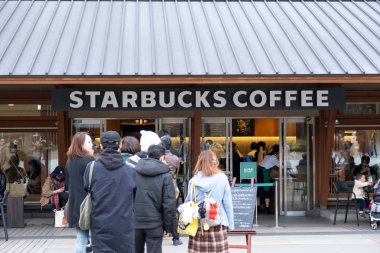 Tokyo, Japonya - 17 Mart 2019: Tokyo, Japonya 'da pembe kiraz çiçekleri veya Sakura bahar sezonu sırasında Starbucks Kahve Ueno Onshi Park kuyruğunda bekleyen müşterileri görmek.