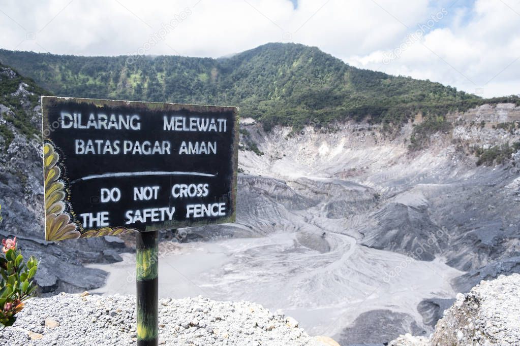 View of the waning sign Do not cross the safety fence in English, as same as Dilarang Melewati Batas Pagar Aman in Indonesian language at Tangkuban Perahu volcano in Bandung, Indonesia.