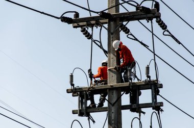 Teknisyenler elektrik direkleri üzerinde yüksek voltaj iletim sistemleri tamir.