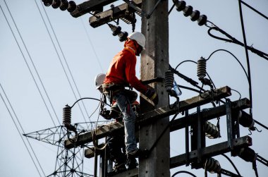 Teknisyenler elektrik direkleri üzerinde yüksek voltaj iletim sistemleri tamir.