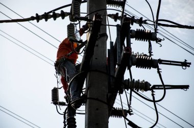 Teknisyenler elektrik direkleri üzerinde yüksek voltaj iletim sistemleri tamir.