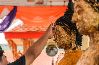 Taylandlı adam, sağ eliyle alnına altın bir Buda heykeli dikmiş..