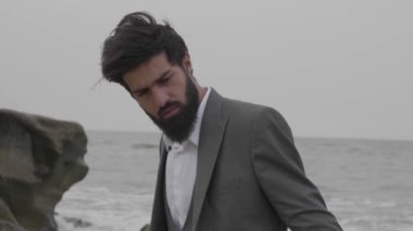 ağır çekim portre acımasız adam kalın sakallı büyük rock sınırsız gökyüzü altında gri deniz karşı etrafa standları