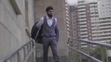 sakallı adam set elbise üzerinde yürüyen kapalı konut alır yavaş şehir içinde metal raylar ile giriş rampası bina