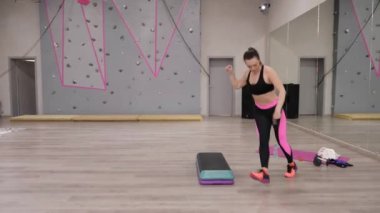 spor giyim güzel genç kadın aerobik yoğun spor salonunda mavi ve siyah platformda adım
