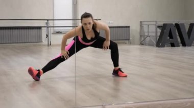 güzel Bayan siyah ve pembe spor giyim ısıtır ve büyük spor salonu aynada yansıtan vücut uzanır