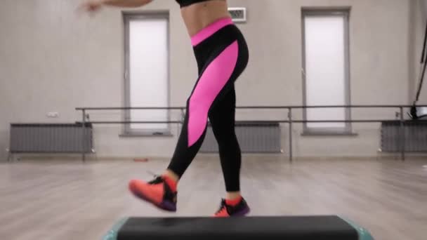 黒ピンクのレギンスでブルネットのポニーテールを持つ若いフィット女性ステップ エアロビクス スロー モーション ビューを閉じる — ストック動画