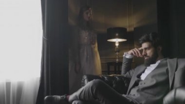 ağır çekim üzgün sakallı adam gri takım elbiseli sarışın kız pembe dantelli elbise geldi ve kanepe sırt üstü eğilir düşünme oturur