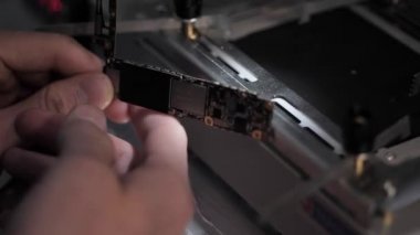 Görünümü Kapat profesyonel tamirci aydınlatma ile siyah tablo karşı siyah ve gümüş iphone anakart tutar