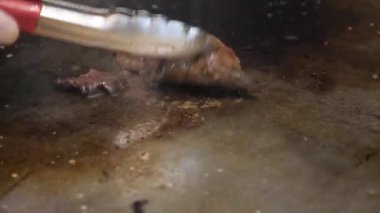 Harika Görünümü Kapat kişi et kızartma yüzeyi Tarih hazırlar ve kırmızı metal Maşa ile döner