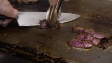 Görünümü Kapat cook et metal bıçak ve Maşa ile keser ve dilimleri kahverengi kızartma yüzey üzerinde hareket eder.