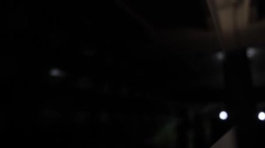 Siyah ekranda beyaz ışıklı ışıklar beliriyor. İnsanların siluetleri karanlık gece klübünün yakın görüntüsünde.