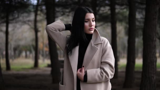 Modelo em casaco elegante corrige cabelo solto em madeira câmera lenta — Vídeo de Stock