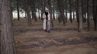 Bahar elbiseli kadın çam ormanlarında ağır çekimde yürüyor.