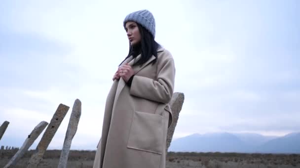 Model in hat and long coat poses in wasteland slow motion — Stock Video