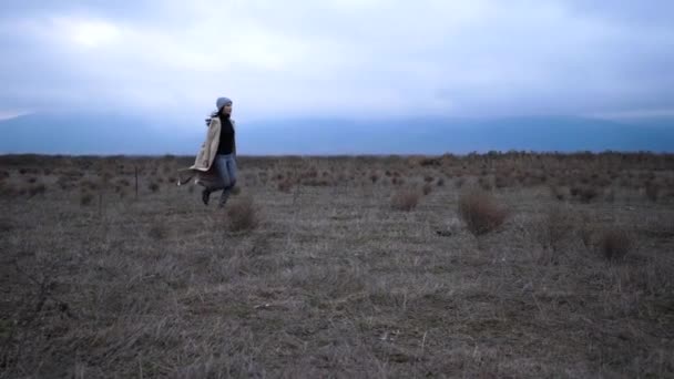 Girl in loose coat runs on meadow in morning slow motion — Stock Video