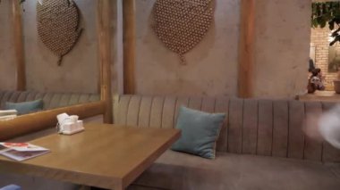 acele genç adam modern kafede ayna yakınında masada yastık ile rahat kanepeye oturur