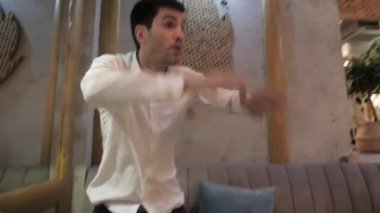 kızgın aç genç adam ayağa kalkar ve modern kafede el çırparak personelin dikkatini çekmeye çalışır