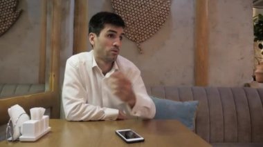 üzgün yakışıklı adam kafede ayna yakınında masada supplication avuç içi jesti ile sipariş almak istiyor